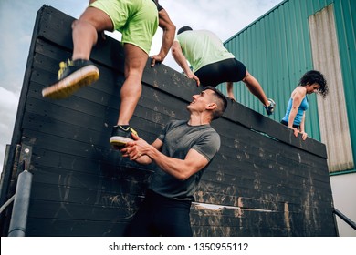 Group Of Participants In An Obstacle Course Climbing A Wall