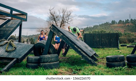 Group of participants in an obstacle course climbing an inverted wall - Powered by Shutterstock