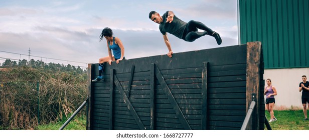 Group Of Participants In An Obstacle Course Climbing A Wall