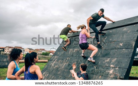 Group of participants in an obstacle course climbing a pyramid obstacle