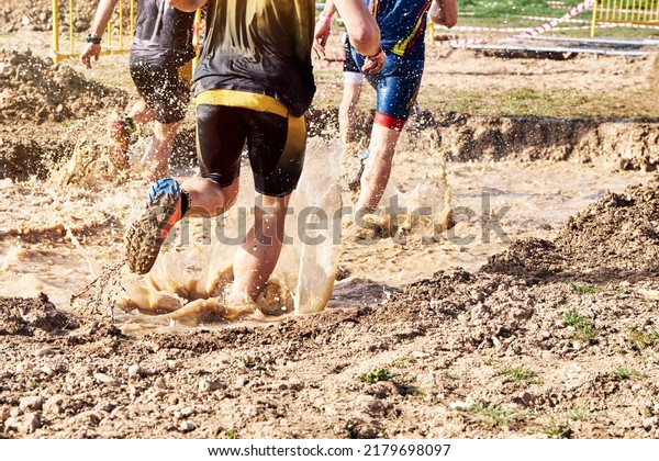 Group\
of participants in an obstacle course race running across a pool of\
water. Spartan race. Concept of hardness and\
effort