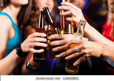 Group of party people - men and women - drinking beer in a pub or bar