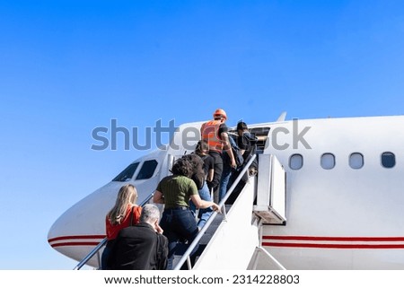 Group of passengers climbing stairs to board plane. 