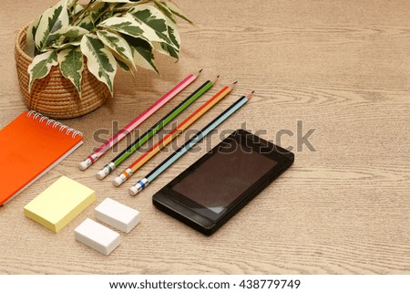 group of pencil ,rubber,mobile phone and note on desk,wooden