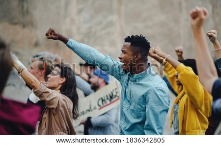 Group of people activists with raised fists protesting on streets, BLM demonstration concept.