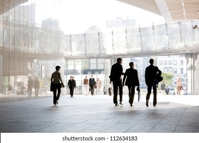 A group of people is against the backdrop of modern buildings. Blurred motion. Silhouette.