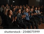 Group of people applauds to speech at business conference. Stage talk at summit meet in crowded modern hall. Caucasian man training at economy forum. Applause of attractive male person in suit indoors