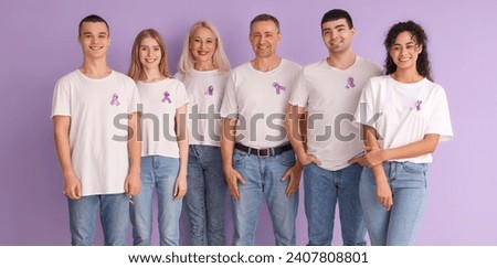Group of people with cancer awareness ribbons on lilac background