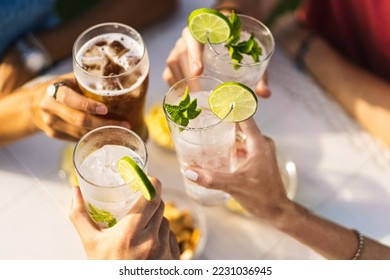 Group of people celebrating toasting with cocktails - cropped detail with focus on hands - lifestyle concept of people, drinks and alcohol - no faces - unrecognizable people