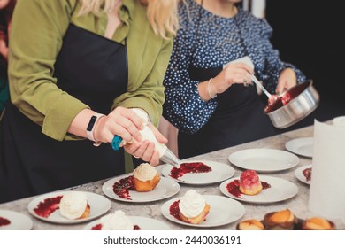 Group of people in a cooking class studio, adults preparing different dishes in the kitchen together, people in aprons learn on culinary master class, chef uniform, hands in gloves, italian cuisine - Powered by Shutterstock