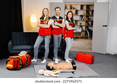 Group of people with cpr dummy looking at camera and smiling after first aid training class.