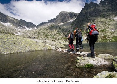 Group Of People Crossing Mountain Pond In Tatra Mountains, Slovakia