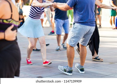 Group of people dancing swing in the street from feet perspective