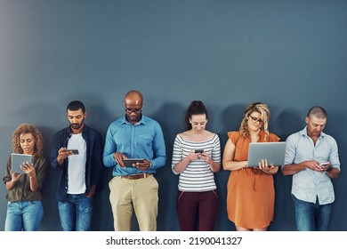 A Group Of People Distracted Due To The Overuse Of Technology Against Gray Studio Background. Many Employees Are Addicted And Obsessed With Social Media With A Dependence On Gadgets Or Devices