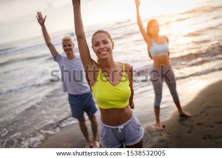 Group of people doing exercises on the beach. Fitness, training, sport and people concept