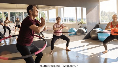 Group of people doing hula hoop during an exercise class in a gym. Healthy sports lifestyle, Fitness, Healthy concept.