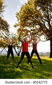 A Group Of People Doing Jumping Jacks In The Park