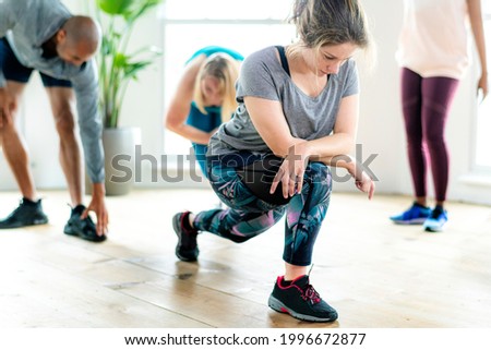 Group of people doing quadriceps stretching in class