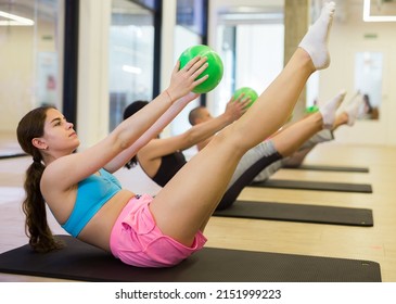Group of people doing v-sits exercise with small pilates balls
