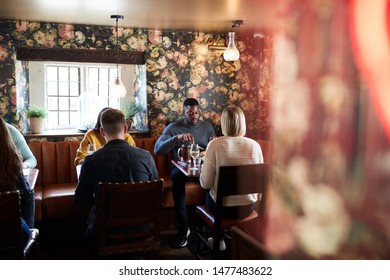 Group Of People Eating In Restaurant Of Busy Traditional English Pub