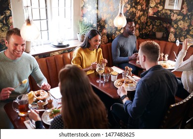 Group Of People Eating In Restaurant Of Busy Traditional English Pub