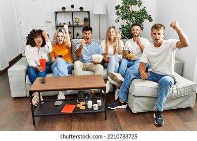 Group Of People Eating Snack Sitting On The Sofa At Home Annoyed And Frustrated Shouting With Anger, Yelling Crazy With Anger And Hand Raised 