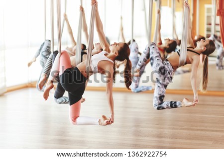 a group of people engaged in a class of yoga Aero in hammocks antigravity