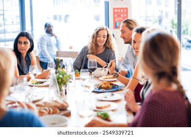 Group of people enjoying a meal at a restaurant. Diverse group dining together, sharing food, and engaging in conversation. Social gathering at a dining table. Diverse people at lunch at restaurant. - Powered by Shutterstock