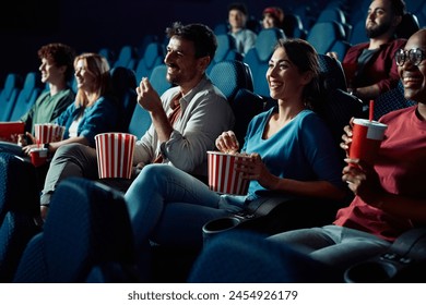 Group of people enjoying in while watching movie and eating popcorn in cinema. Focus is on woman.  - Powered by Shutterstock