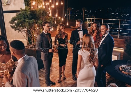 Group of people in formalwear communicating and smiling while spending time on luxury party