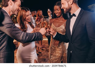 Group Of People In Formalwear Toasting With Champagne And Smiling While Spending Time On Luxury Party