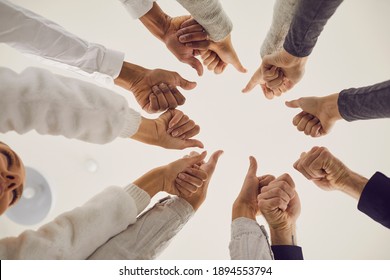Group of people giving thumbs-up all together. Team celebrating teamwork and success, approving of quality product, voting for good idea or useful suggestion. Low angle of human hands joined in circle