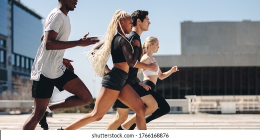 Group Of People Going Running Workout Together In The City. Diverse Group Of Street Runners Running In The City.