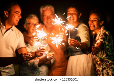 group of people have fun celebrating together new year eve or birthday with sparkles light and fireworks in friendship outdoor at evening time - family and friends different ages celebrate friendly  - Powered by Shutterstock