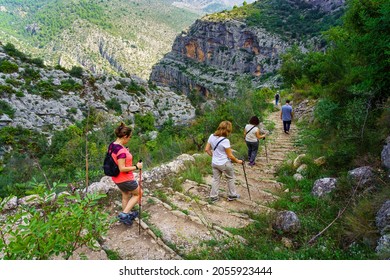 Group Of People Hiking On The Mountain Path Going Down Steps.