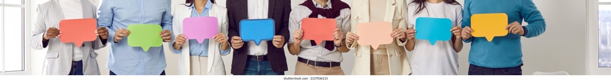 Group of people holding colorful message bubbles. Team of entrepreneurs with red, green, purple, blue, yellow mock up speech balloons sharing different opinions. Cropped shot. Banner header background - Shutterstock ID 2137036115