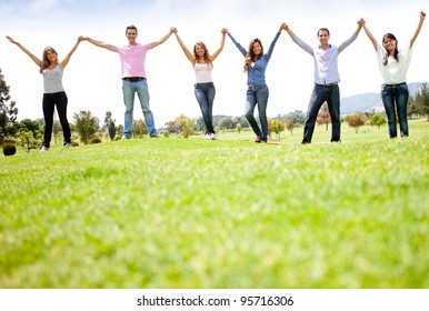 Group Of People Holding Hands At The Park And Smiling