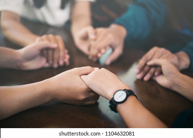 Group of people holding hands and praying.
