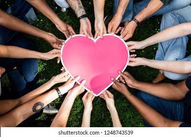 Group of people holding a pink heart icon - Shutterstock ID 1248743539