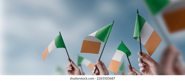 A group of people holding small flags of the Ireland in their hands.