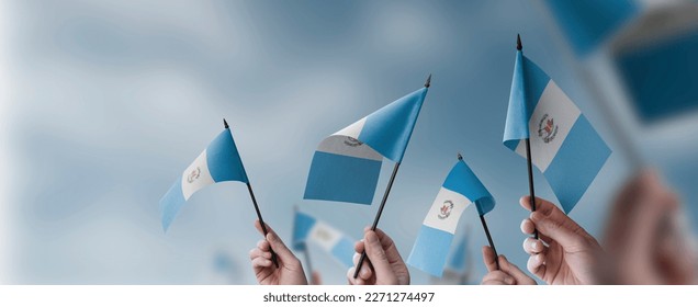 A group of people holding small flags of the Guatemala in their hands.