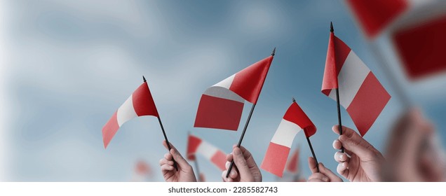 A group of people holding small flags of the Peru in their hands.