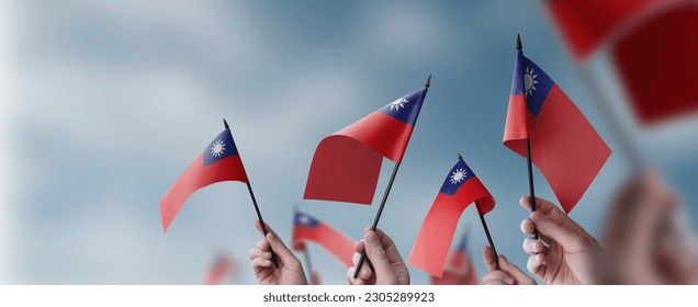 A group of people holding small flags of the Taiwan in their hands.