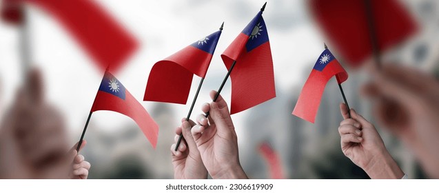 A group of people holding small flags of the Taiwan in their hands.