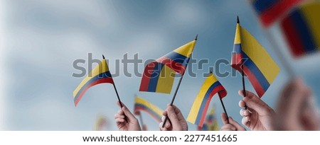 A group of people holding small flags of the Colombia in their hands.