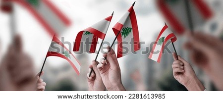 A group of people holding small flags of the Lebanon in their hands.