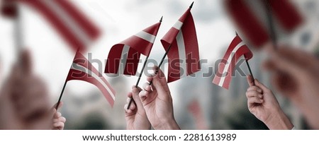A group of people holding small flags of the Latvia in their hands.