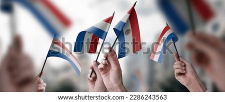 A group of people holding small flags of the Paraguay in their hands.