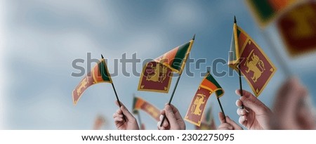 A group of people holding small flags of the Sri Lanka in their hands.