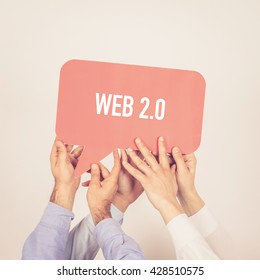 A group of people holding the Web 2.0 written speech bubble